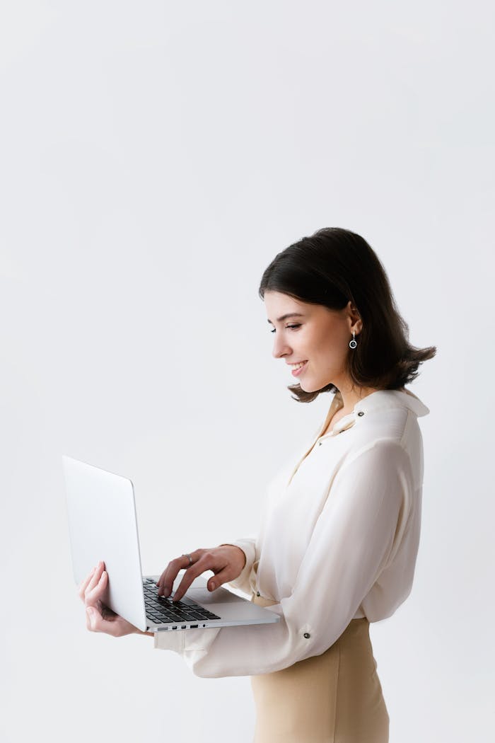 Side view of a businesswoman typing on a laptop against a white background in a studio.